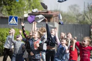 bambini a partire dal scuola materna gettare su loro cappelli. foto