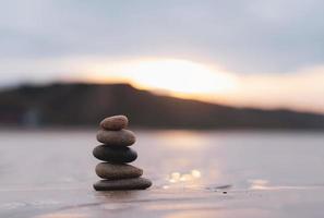 zen pila pietra su mare sabbia spiaggia con sfocato tramonto immagine di sfondo paesaggio ciottolo roccia Torre piramide concetto per stabilità, armonia, vita equilibrio, meditazione, zen piace foto