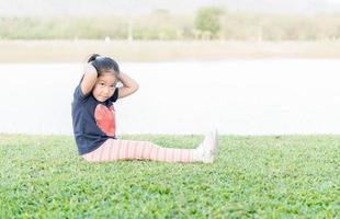 carino asiatico ragazza esercizio su verde erba foto