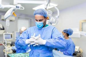 ritratto di maschio chirurgo con squadra di medici su sfondo nel operazione camera. foto
