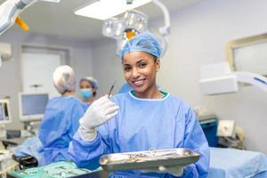 ritratto di femmina donna infermiera chirurgo o personale membro vestito nel chirurgico scrub toga maschera e capelli netto nel ospedale operativo camera Teatro fabbricazione occhio contatto sorridente lieta contento guardare a telecamera foto