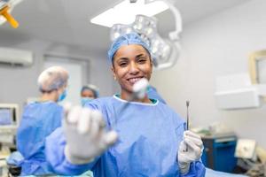 ritratto di contento donna chirurgo in piedi nel operativo camera, pronto per opera su un' paziente. femmina medico lavoratore nel chirurgico uniforme nel operazione Teatro. foto