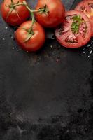 disposizione di deliziosi pomodori freschi con copia spazio su sfondo nero foto