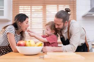 mamma e papà nel il cucina di il Casa con loro piccolo bambini. avere un' bene tempo fabbricazione cena insieme. foto