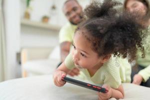 poco bambini giocare e imparare cose nel il largo mondo su tavoletta. con genitori per sorvegliare e Aiuto nel il vivente camera di il Casa su vacanza foto