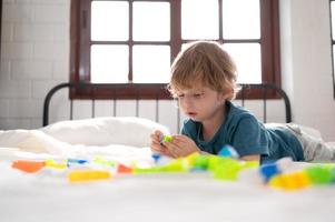 poco ragazzo nel il suo Camera da letto con un' nuovo giocattolo acquistato di il suo genitori per Aiuto lui Ottimizzare il suo pensiero abilità. foto