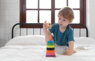 poco ragazzo nel il suo Camera da letto con un' nuovo giocattolo acquistato di il suo genitori per Aiuto lui Ottimizzare il suo pensiero abilità. foto