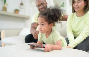 poco bambini giocare e imparare cose nel il largo mondo su tavoletta. con genitori per sorvegliare e Aiuto nel il vivente camera di il Casa su vacanza foto