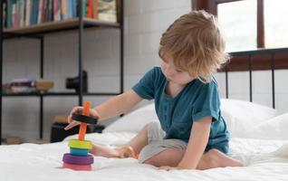 poco ragazzo nel il suo Camera da letto con un' nuovo giocattolo acquistato di il suo genitori per Aiuto lui Ottimizzare il suo pensiero abilità. foto