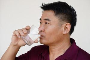 asiatico uomo è potabile acqua a partire dal bicchiere. concetto bevanda acqua per Salute, bevanda dopo pasti, medicinali , durante il giorno o dopo ottenere su nel il mattina. Salute cura, alleviare sete foto