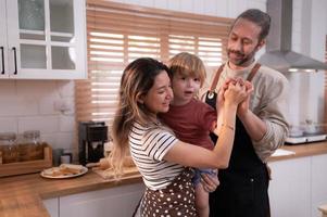 mamma e papà nel il cucina di il Casa con loro piccolo bambini. avere un' bene tempo fabbricazione cena insieme. foto