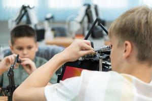 bambini utilizzando il mano robot tecnologia, studenti siamo studiando tecnologia, quale è uno di il stelo corsi. foto