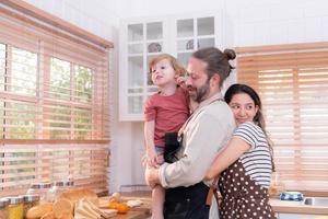 mamma e papà nel il cucina di il Casa con loro piccolo bambini. avere un' bene tempo fabbricazione cena insieme. foto