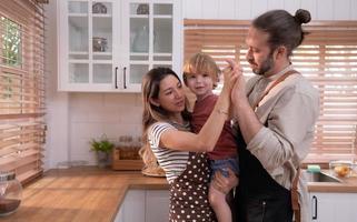 mamma e papà nel il cucina di il Casa con loro piccolo bambini. avere un' bene tempo fabbricazione cena insieme. foto