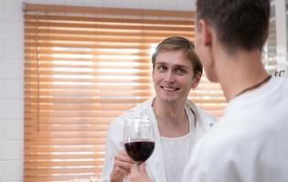 lgbt giovane coppia celebrare il giorno di amore fra ogni altro con bene vino nel il cucina di il Casa foto