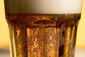 primo piano bicchiere di birra fredda con bolle dorate