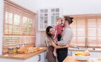 mamma e papà nel il cucina di il Casa con loro piccolo bambini. avere un' bene tempo fabbricazione cena insieme. foto