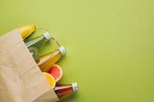 sacchetto di carta flatlay con succhi di frutta su sfondo verde