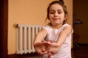 avvicinamento stile di vita ritratto di un adorabile caucasico poco bambino ragazza allungamento braccia e sorridente guardare a telecamera foto