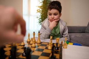 scacchi gioco per intelligente mente. bello intelligente pensieroso adolescenziale ragazzo guardare pensieroso a scacchi asse, pensiero di scacchi strategia mentre giocando foto