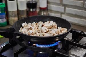 tritato funghi siamo fritte nel frittura padella su gas stufa foto