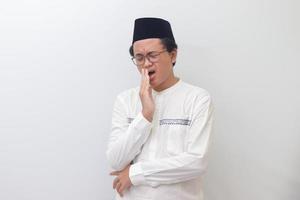 ritratto di giovane asiatico musulmano uomo sbadigli con mano copertura il suo bocca. isolato Immagine su bianca sfondo foto