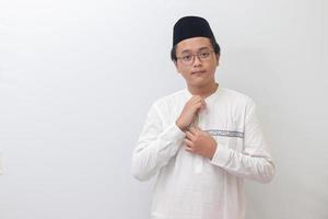 ritratto di giovane asiatico musulmano uomo provando per fix il suo camicia pulsanti. isolato Immagine su bianca sfondo foto
