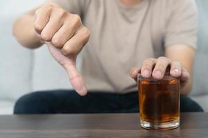 uomo rifiuta dire no e evitare per bevanda un alcool whisky , sosta mano cartello maschio, alcolismo trattamento, alcool dipendenza, smettere liquore, fermare potabile alcol. rifiuto bicchiere liquore, malsano, rifiutare foto