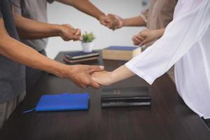 gruppo di persone Tenere mani nel ricordo di Dio su il tavolo Là è un' Bibbia, rispetto, spiritualità e religione. cristiano sfondo formazione scolastica ricerca o studiando il Bibbia. foto