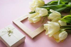 giallo tulipano fiori, foto telaio e regalo scatola siamo disposte su un' rosa sfondo. il Visualizza a partire dal il superiore, liscio posizione. il concetto di primavera. Da donna giorno.