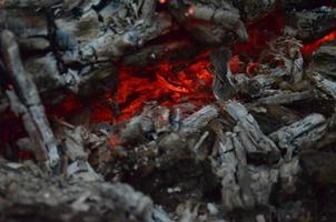 raggiante brace nel caldo rosso colore. il caldo brace nel il mezzo di bruciato legna registri. legna da ardere ardente su griglia. natura struttura. foto