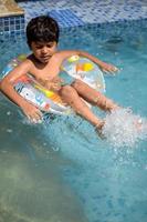 contento indiano ragazzo nuoto nel un' piscina, ragazzo indossare nuoto costume lungo con aria tubo durante caldo estate vacanze, bambini ragazzo nel grande nuoto piscina. foto