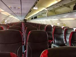 vuoto confortevole nero e rosso posti a sedere con cinture di sicurezza nel moderno aereo cabina durante volo a giorno foto