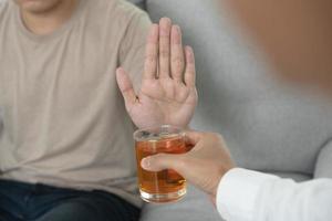 uomo rifiuta dire no e evitare per bevanda un alcool whisky , sosta mano cartello maschio, alcolismo trattamento, alcool dipendenza, smettere liquore, fermare potabile alcol. rifiuto bicchiere liquore, malsano, rifiutare foto