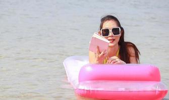 bella donna asiatica che gode del relax in spiaggia. belle ragazze si divertono a giocare in acqua sulla spiaggia estiva foto