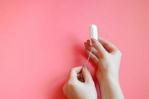 donna è Tenere igienico cotone tampone nel sua mani. foto