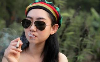 yong Asia donna fumo marijuana a canapa albero pianta sfondo foto