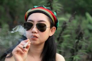 yong Asia donna fumo marijuana a canapa albero pianta sfondo foto