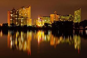 notte città con riflessione di case nel il fiume foto