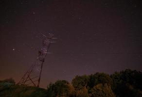 paesaggio con elettricità pilone contro stellato cielo foto