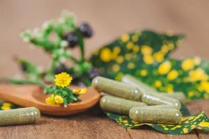 erbaceo medicina capsule a partire dal erba su rustico di legno tavolo per salutare mangiare e bene vita ,morbido messa a fuoco. foto