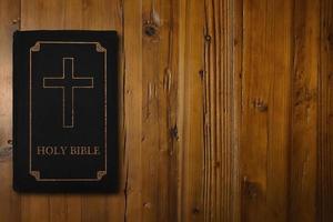 Bibbia con un' dorato attraversare su un' scrivania foto