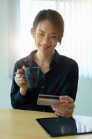 donna che tiene caffè e carta di credito foto