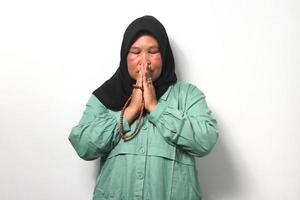 mezzo anziano asiatico donne indossare hijab prega per Dio e Tenere preghiera perline isolato al di sopra di bianca sfondo. foto