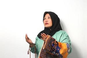 mezzo anziano asiatico donne indossare hijab prega per Dio e Tenere preghiera perline e giocatore stuoia isolato al di sopra di bianca sfondo. foto