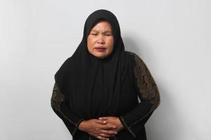 malsano mezzo anziano asiatico donne indossare hijab si sente così malato sofferenza a partire dal acuto addominale, mestruale dolore o i problemi con digestione foto