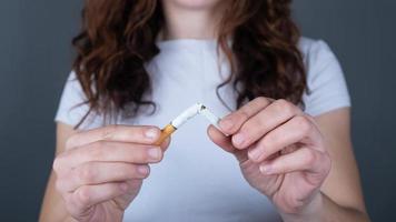donna che tiene una sigaretta rotta, smettere di fumare segno