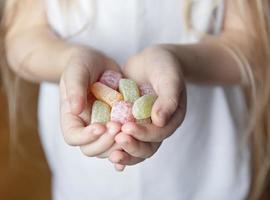 bambino che tiene caramelle, gelatina in mano foto