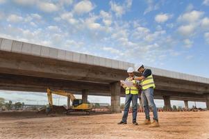 asiatico architetto e maturo supervisori incontro a costruzione luogo multietnico lavoratori e ingegneri discutere piani Due costruzione lavoratori Lavorando insieme mentre visitare autostrada costruzione foto