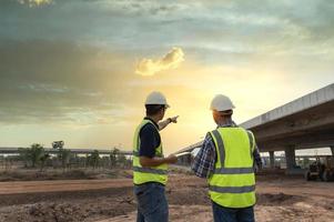 asiatico architetto e maturo supervisori incontro a costruzione luogo multietnico lavoratori e ingegneri discutere piani Due costruzione lavoratori Lavorando insieme mentre visitare autostrada costruzione foto